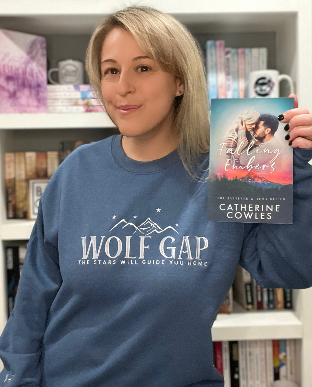 a woman holding up a book in front of a bookshelf